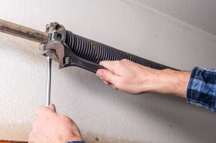 Close-up of a torsion spring being adjusted on a residential garage door in Toms River, showing the type of spring repair Surfside Garage Doors handles for Ocean County homeowners.