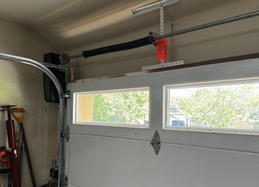 Garage door track misalignment visible along the horizontal track and torsion spring assembly inside a Monmouth County, NJ home, serviced by Surfside Garage Doors.